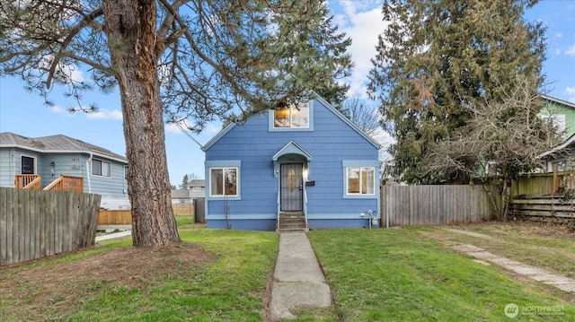 bungalow-style home with fence and a front lawn