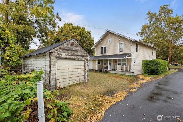 traditional-style home featuring a garage, a porch, and an outbuilding