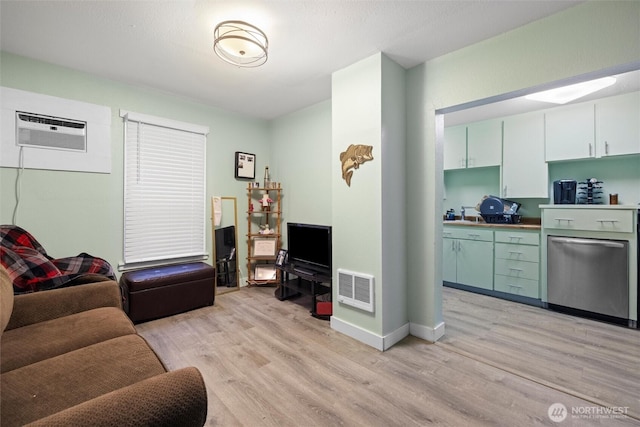 living area featuring a wall unit AC, light wood-style floors, baseboards, and visible vents