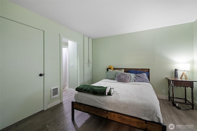 bedroom with baseboards, visible vents, and wood finished floors