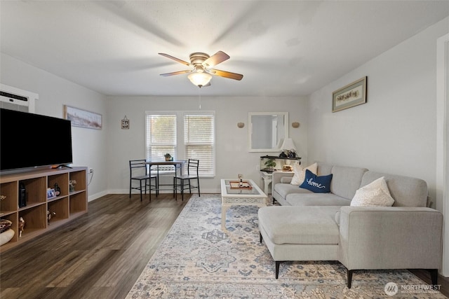 living room featuring wood finished floors, a ceiling fan, and baseboards