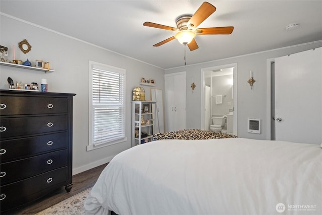 bedroom with heating unit, connected bathroom, ornamental molding, and dark wood-style flooring