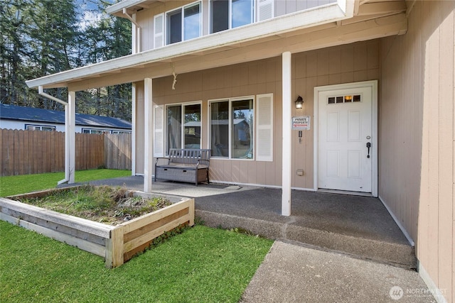 property entrance with fence and a lawn