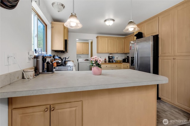 kitchen featuring light brown cabinets, a sink, independent washer and dryer, a peninsula, and stainless steel fridge with ice dispenser