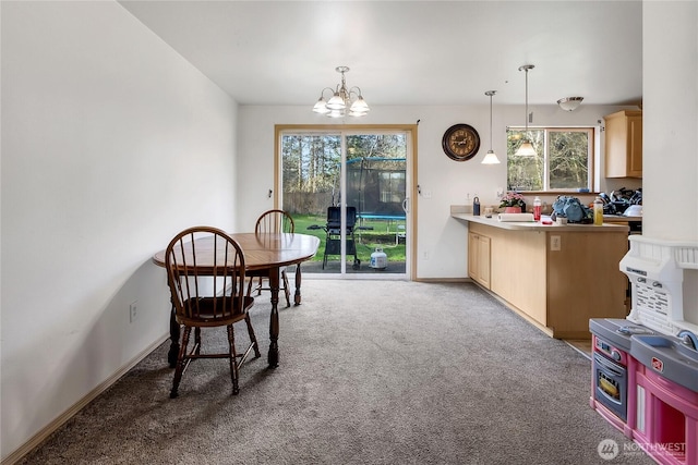 dining space featuring light carpet, plenty of natural light, baseboards, and a notable chandelier