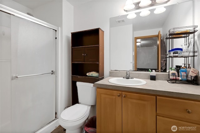 bathroom featuring toilet, a stall shower, visible vents, and vanity