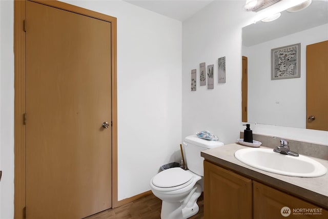 half bath featuring vanity, toilet, and wood finished floors