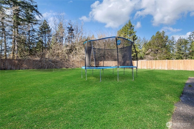 view of yard featuring a trampoline and fence