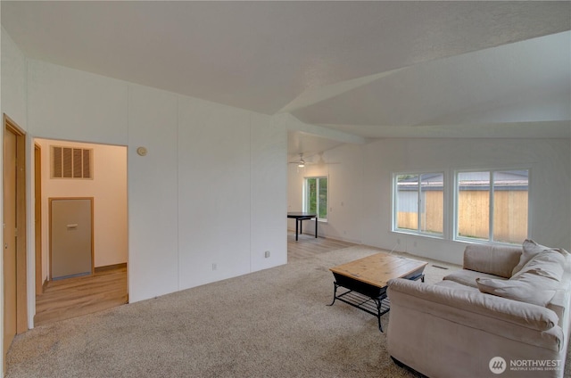 living area featuring carpet, visible vents, and lofted ceiling