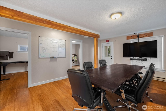 office featuring light wood-type flooring, baseboards, and a textured ceiling