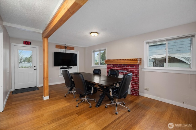 dining room featuring light wood finished floors, baseboards, and a textured ceiling