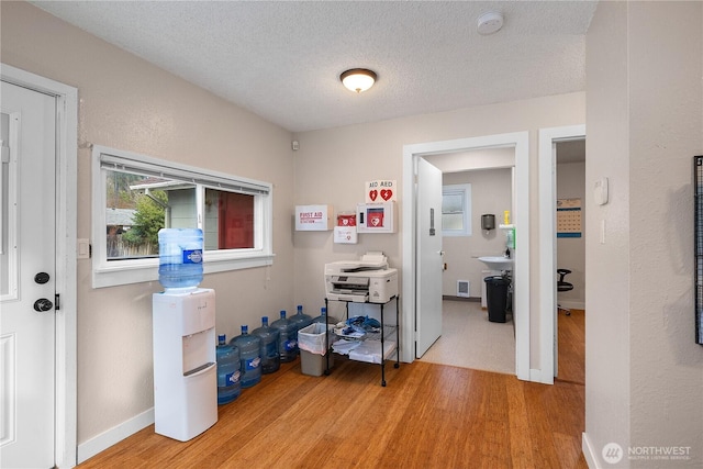 home office with a textured ceiling, light wood-style flooring, and baseboards