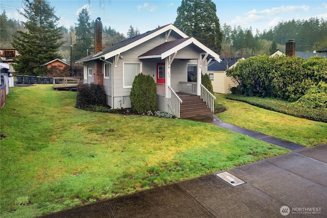 view of front of home featuring a porch, a chimney, and a front lawn