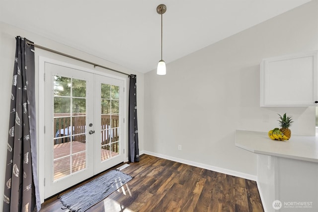 unfurnished dining area with dark wood-style floors, french doors, lofted ceiling, and baseboards