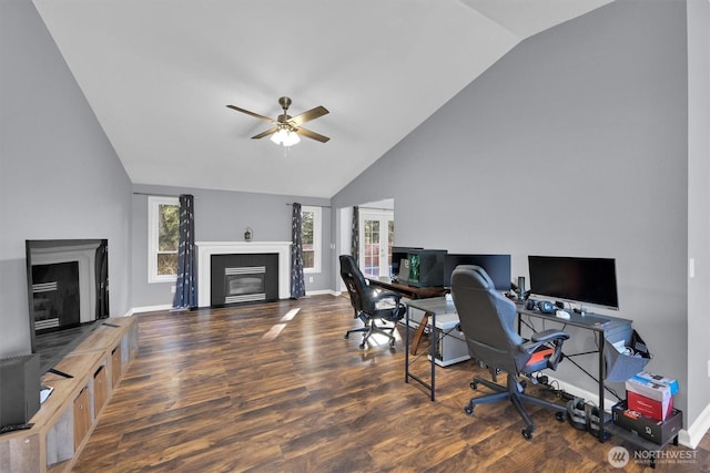 home office with a fireplace with flush hearth, a ceiling fan, baseboards, and wood finished floors