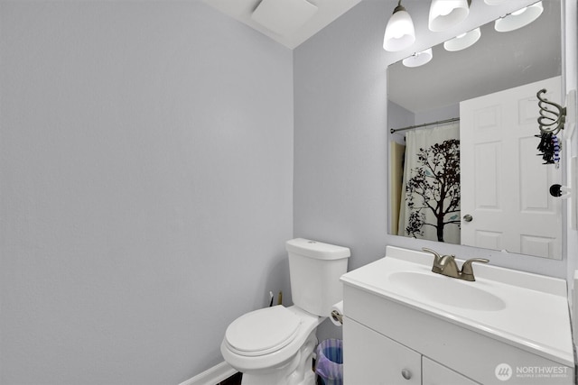 bathroom featuring toilet, baseboards, and vanity