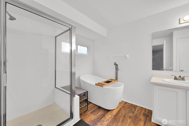 bathroom featuring a stall shower, a freestanding bath, vanity, and wood finished floors