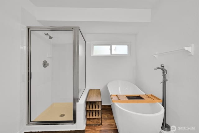 bathroom featuring a stall shower, wood finished floors, and a soaking tub