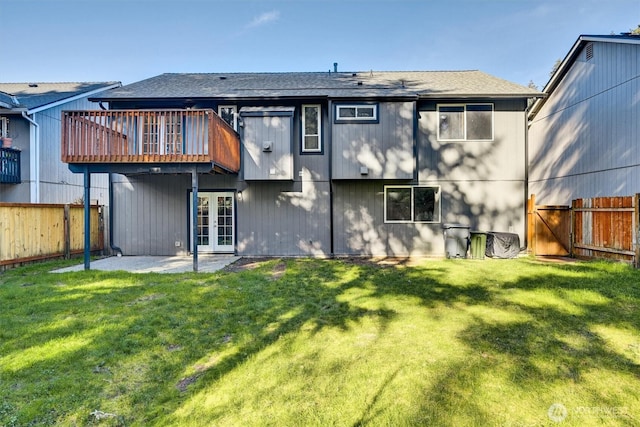 rear view of house with a yard, french doors, and a fenced backyard