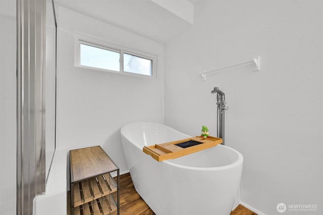 full bathroom featuring a soaking tub, baseboards, and wood finished floors