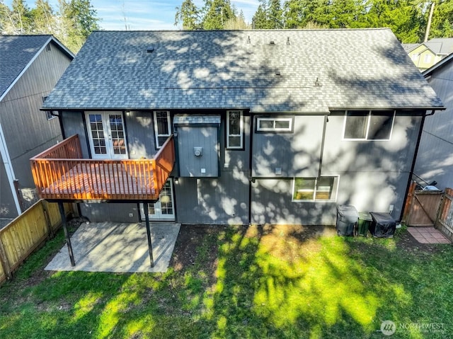 rear view of property featuring fence, french doors, roof with shingles, a lawn, and a patio area