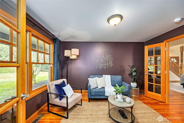 living area featuring french doors, visible vents, stairway, wood finished floors, and baseboards