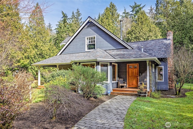 view of front of property with a porch, a front yard, roof with shingles, and a chimney