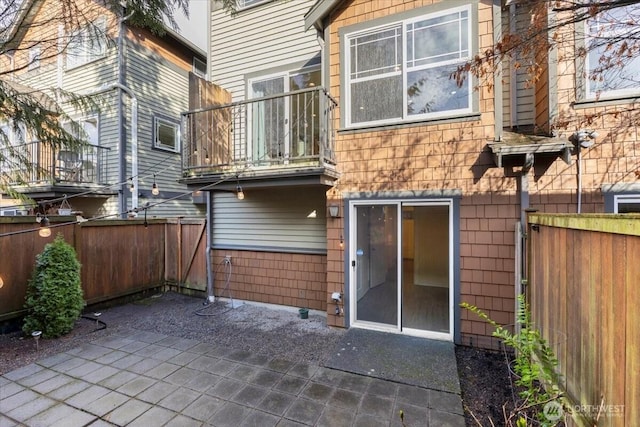 back of house with a balcony, a fenced backyard, and a patio