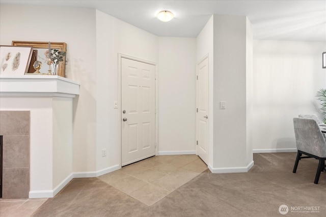 entryway with carpet floors, baseboards, and a tile fireplace