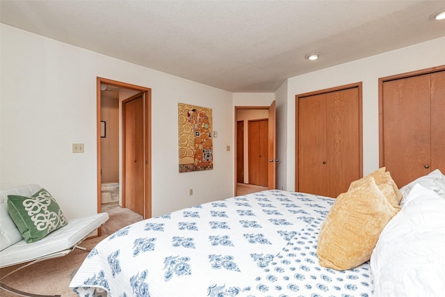 bedroom with light carpet, ensuite bath, and two closets