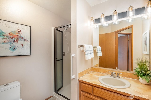 bathroom with a shower stall, toilet, and vanity