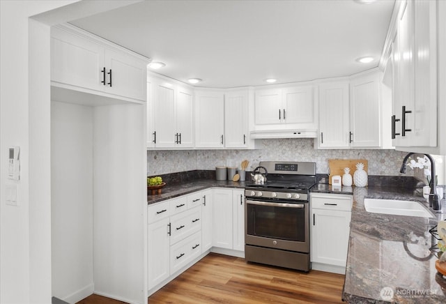 kitchen featuring a sink, white cabinets, custom exhaust hood, stainless steel range with gas cooktop, and dark stone countertops