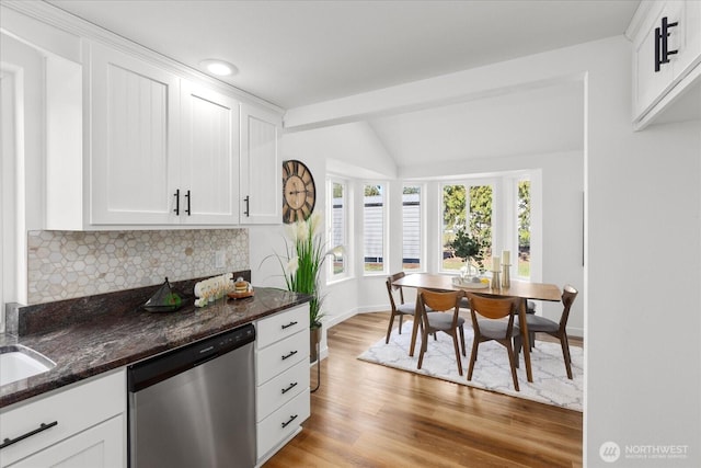 kitchen with lofted ceiling, white cabinetry, light wood-type flooring, dishwasher, and tasteful backsplash