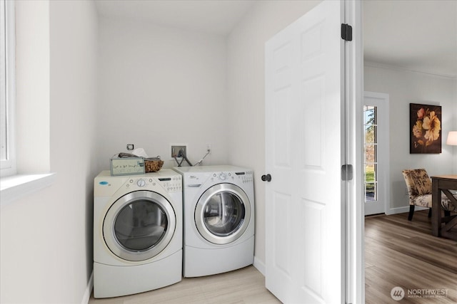 laundry area featuring laundry area, washing machine and dryer, light wood-style flooring, and baseboards