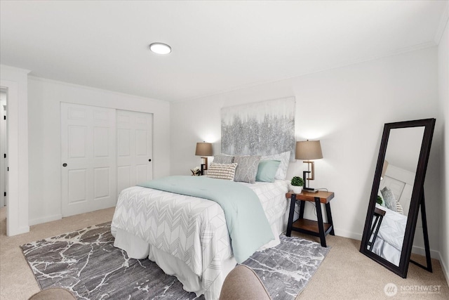 carpeted bedroom with ornamental molding, a closet, and baseboards