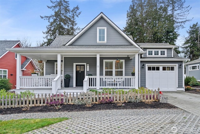 view of front facade featuring a garage, covered porch, a shingled roof, and decorative driveway