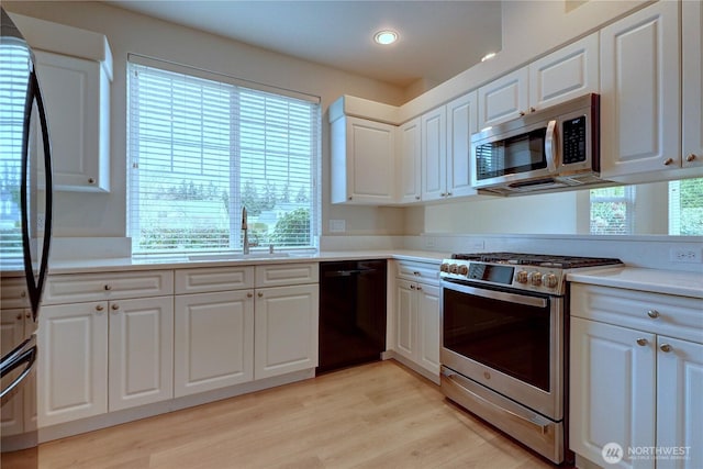 kitchen with black appliances, a healthy amount of sunlight, light countertops, and a sink