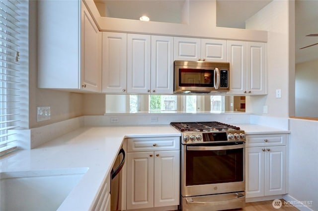 kitchen featuring appliances with stainless steel finishes, white cabinetry, light countertops, and a sink