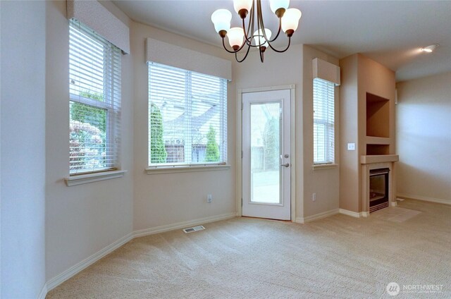 entryway with visible vents, a fireplace with flush hearth, a notable chandelier, carpet floors, and baseboards