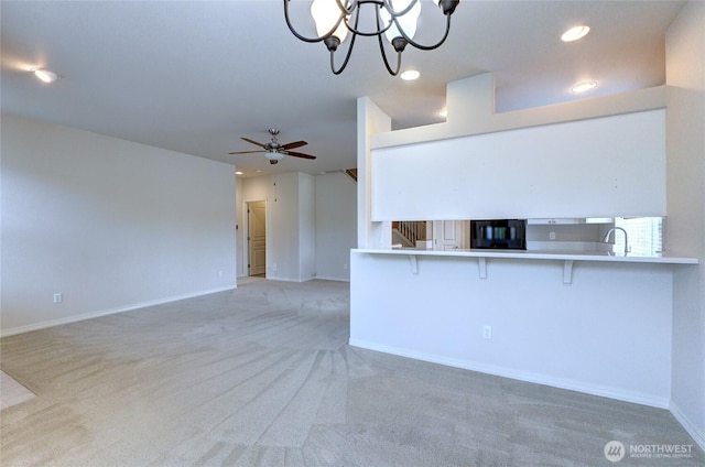 unfurnished living room featuring baseboards, stairs, recessed lighting, ceiling fan with notable chandelier, and a sink