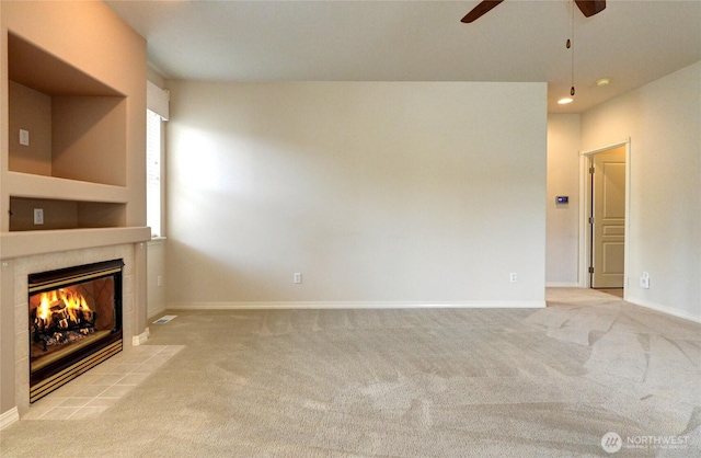 unfurnished living room with a tiled fireplace, carpet flooring, and baseboards