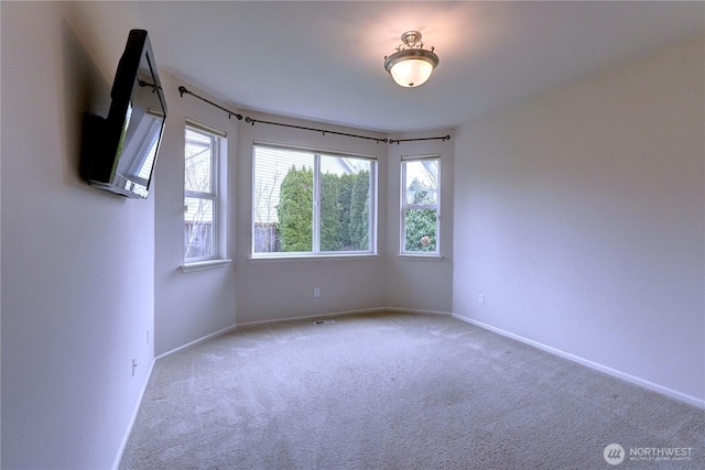 spare room with baseboards, carpet floors, and visible vents