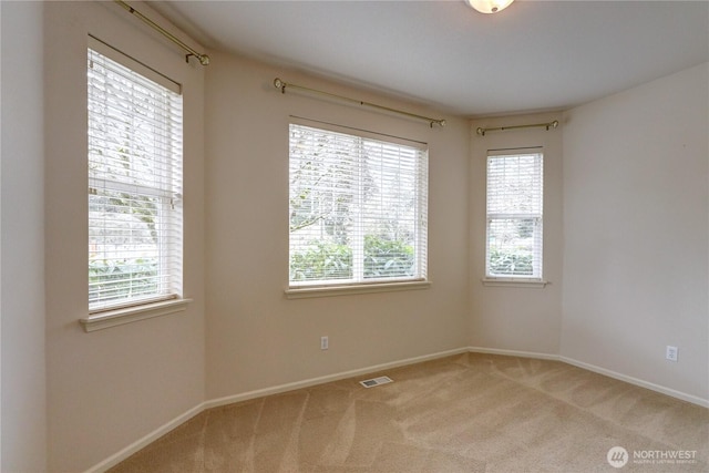 carpeted spare room with visible vents and baseboards