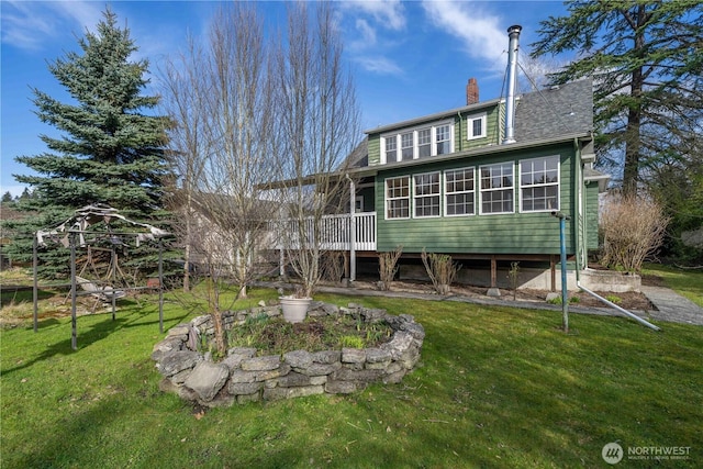 back of house featuring a sunroom, a shingled roof, a chimney, and a yard