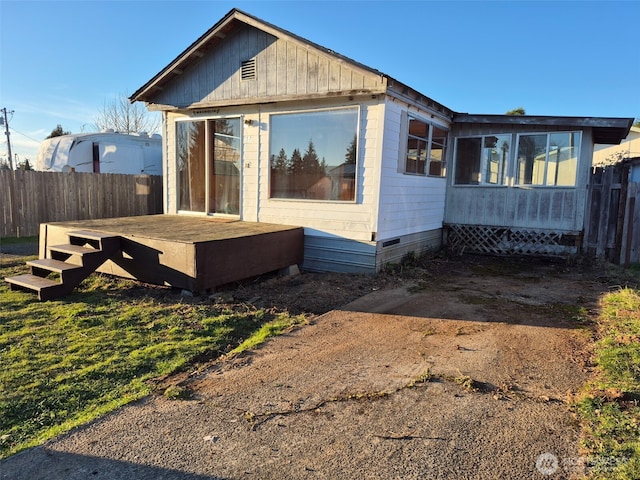 view of side of home featuring a deck, crawl space, and fence