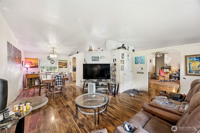 living area with ceiling fan with notable chandelier, arched walkways, and wood finished floors