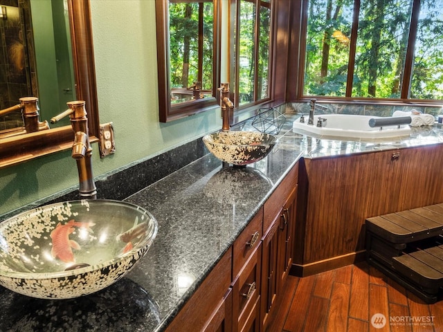 full bathroom featuring a textured wall, double vanity, wood finished floors, and a sink