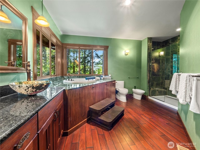 bathroom with toilet, hardwood / wood-style flooring, a bidet, and a stall shower