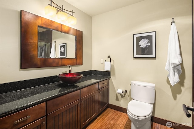 bathroom featuring toilet, baseboards, wood finished floors, and vanity