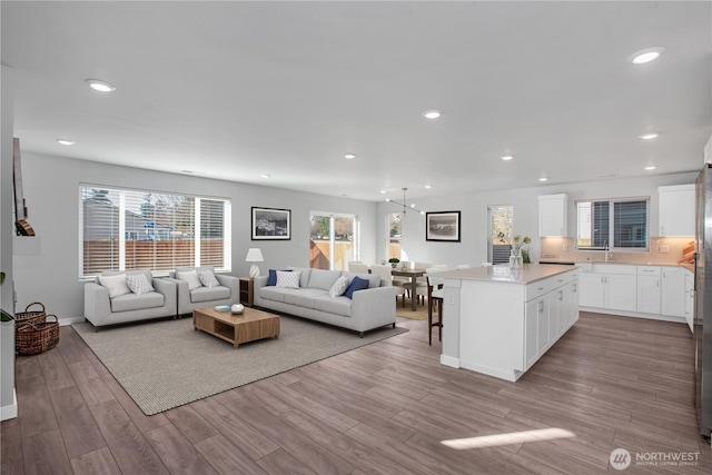 living area with baseboards, wood finished floors, and recessed lighting